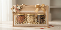 NutriTohffa Premium Diwali Hamper — three glass jars of almonds, cashew W240 and protein bar in a jute gift bag with lace trim and gold ribbon bow