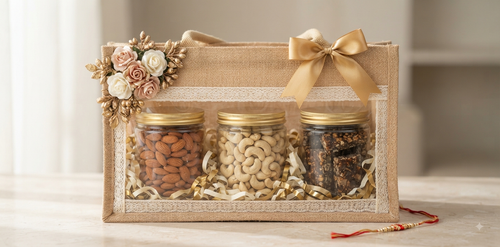 NutriTohffa Premium Diwali Hamper — three glass jars of almonds, cashew W240 and protein bar in a jute gift bag with lace trim and gold ribbon bow